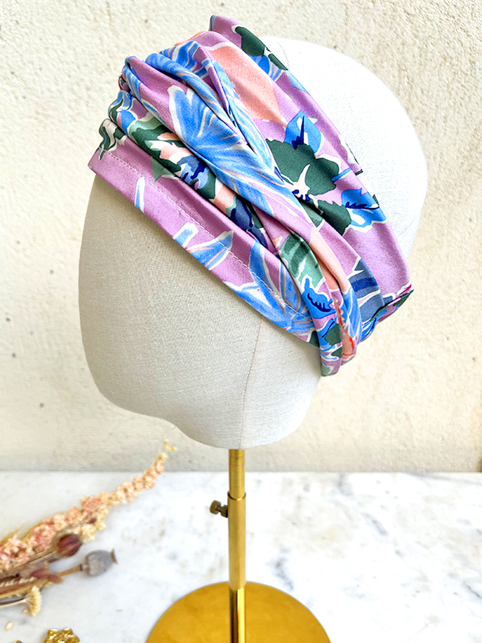Colorful floral turban-style headwrap wrapped around a beige mannequin head on a display stand