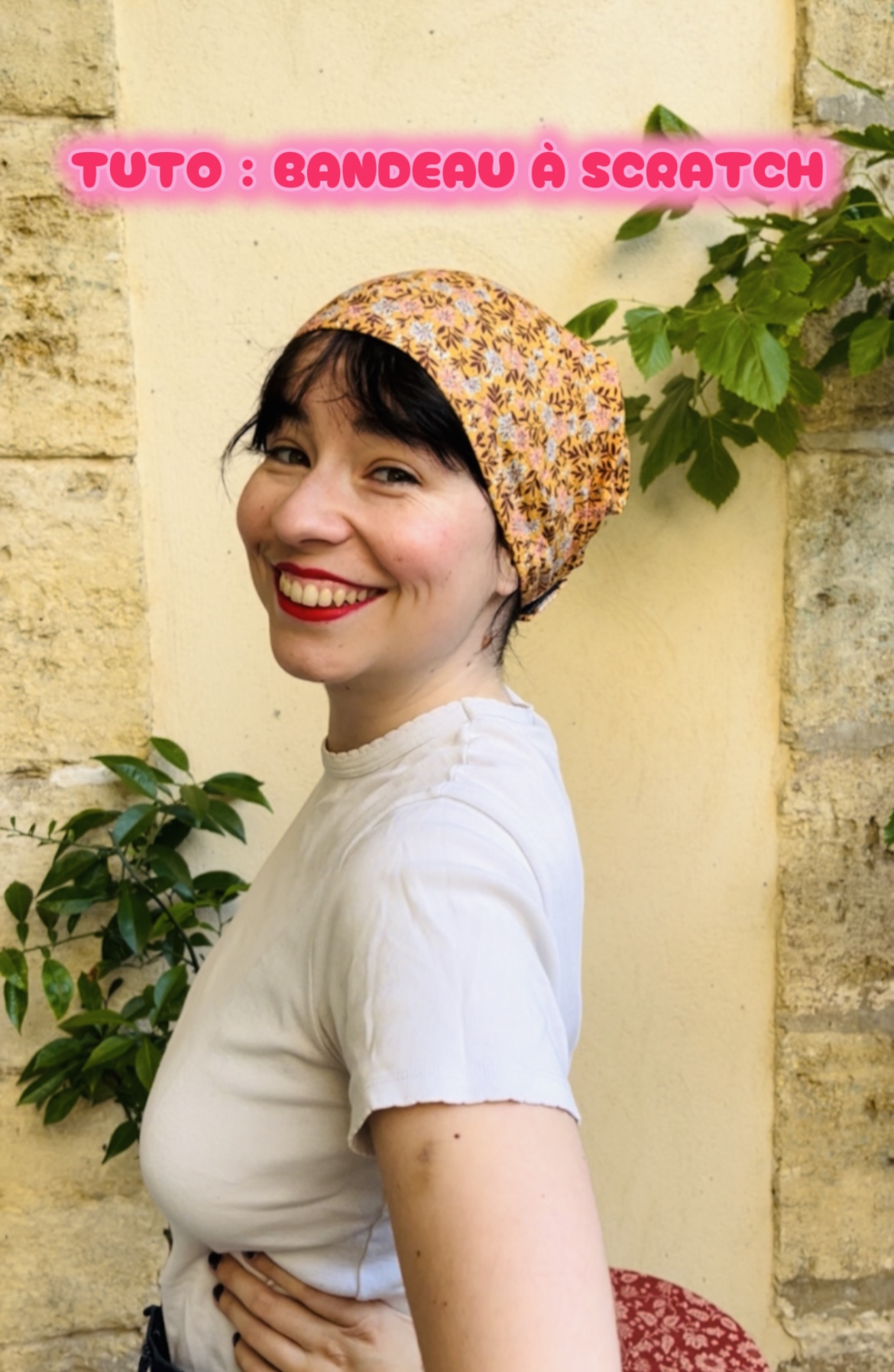 Smiling woman in a floral headscarf poses by a beige wall; pink text overlay reads 'TUTO : BANDEAU À SCRATCH'.